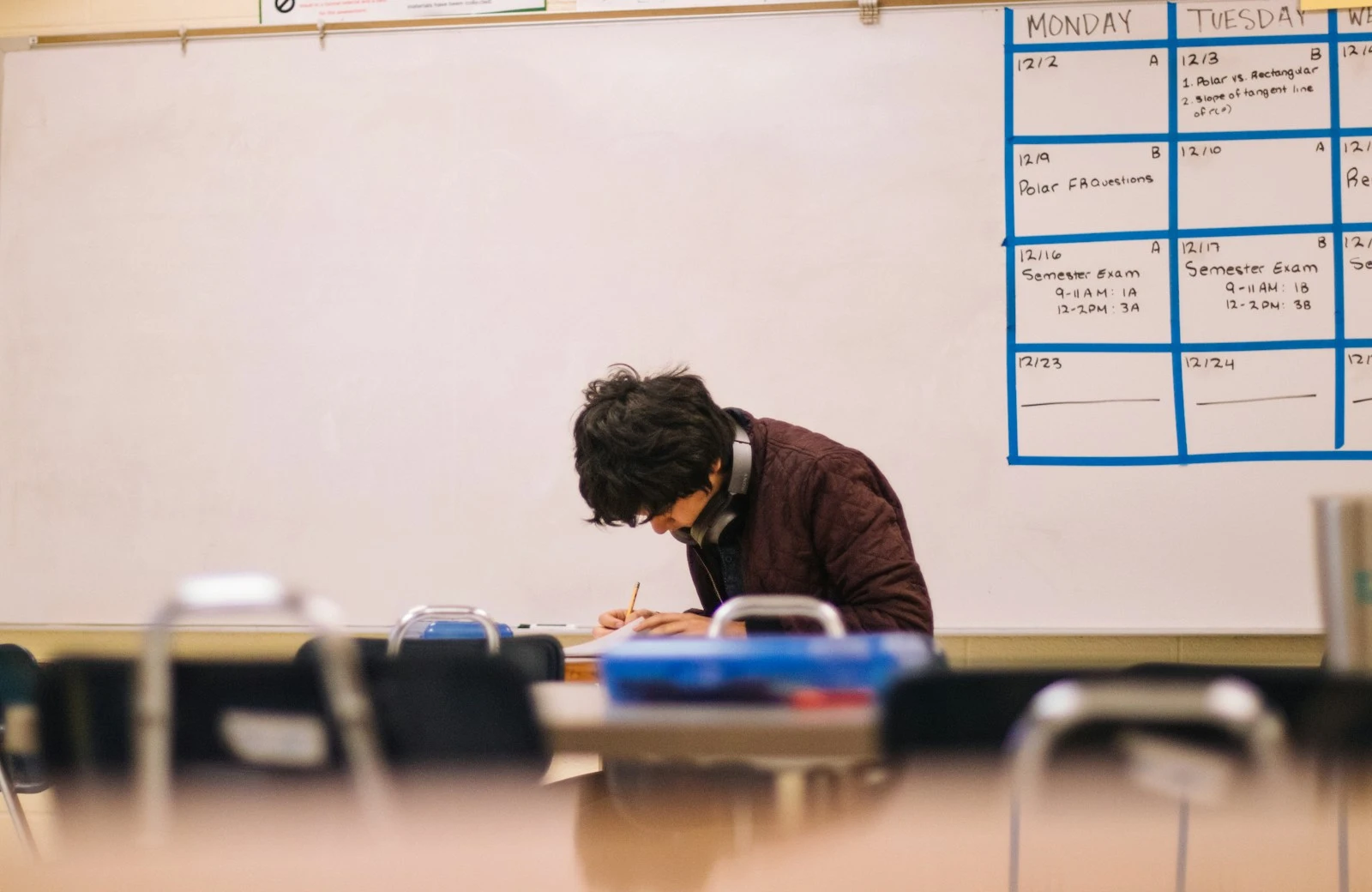 man in brown sweater sitting on chair in an international university after receivng appropriate student loan