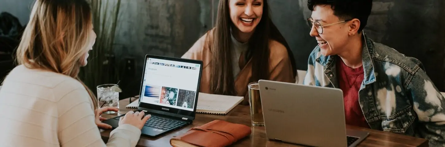 three people sitting in front of table laughing together after receiving correct student loan for their international education